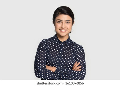 Head shot studio portrait millennial pleasant attractive smiling indian ethnicity confident student, young specialist, intern or employee looking at camera, isolated on grey studio background.