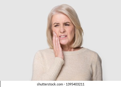 Head Shot Studio Portrait Senior Blond Female Pose On Grey White Background, Touches Cheek Suffering From Sudden Tooth Pain Feels Unhealthy Unhappy Need Dental Service Help, Medical Insurance Concept