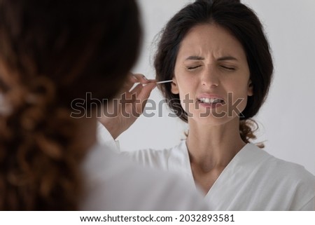 Head shot unhappy millennial hispanic latina woman using cotton bud or stick, cleaning ears after shower, feeling pain doing personal hygienic procedures at home, earache otitis health problems. Foto stock © 