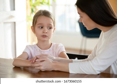 Head Shot Unhappy Small Child Girl Sitting At Table With Worrying Mother, Sharing School Problems. Compassionate Caring Attentive Mommy Having Trustful Conversation With Unhappy Offended Daughter.