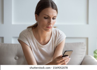 Head Shot Unhappy Thoughtful Woman Looking At Cellphone Screen, Waiting For Call From Boyfriend. Pensive Millennial Lady Reading Sms Or Email With Bad News, Checking Social Networks, Sitting At Home.