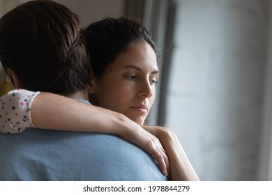Head shot unhappy thoughtful young woman cuddling husband, feeling stressed after conflict, thinking of psychological problems in family relations, upset wife suspecting betrayal or cheating.