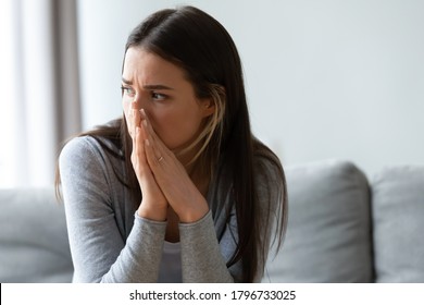 Head Shot Unhappy Young Woman Looking Away, Feeling Doubtful Confused About Difficult Decision. Depressed Millennial Lady Suffering From Personal Psychological Problem, Sitting On Sofa Indoors.