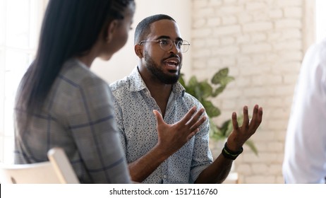 Head shot young african american male psychologist meeting patients at group therapy. Serious mixed race counselor giving advices to employees. Confident business coach training staff at office. - Shutterstock ID 1517116760
