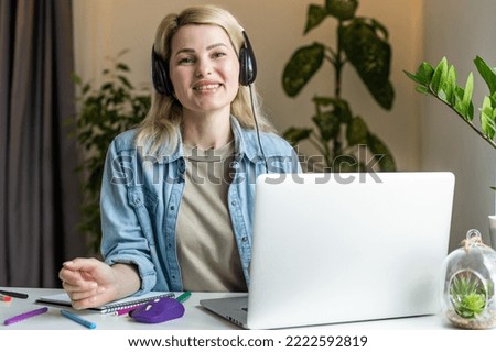 Head shot young happy woman sitting at desk, working on computer at home. Pleasant attractive smiling lady looking at laptop screen, shopping, chatting in social networks, studying online remotely
