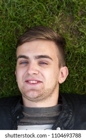 Head Shot Of A Young Man Lying On Grass And Smiling. Close Up. Portrait. Overhead Shot.