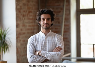 Head shot young millennial Hispanic confident man. Handsome brunette guy pose alone at workplace or loft apartment look at camera. Professional occupation, freelance portrait, homeowner person concept