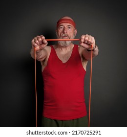 Head And Shoulder Portrait Of Senior Man (in Late 60s) Exercising With Resistance Band,  Fitness Over 60 Concept