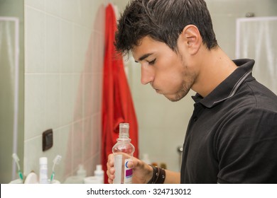 Head And Shoulders Close Up Of Attractive Young Man With Dark Hair Rinsing With Mouth Wash In Bathroom As Part Of Morning Grooming Routine