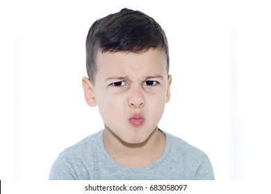 Head and shoulders of a dark haired, brown eyed little boy with a very grumpy face.