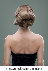 A Head And Shoulders Image Of A Young Woman, From The Back. Her Hair Is Long And Blonde And She Is Showing An Interesting, Wavy Hairstyle.