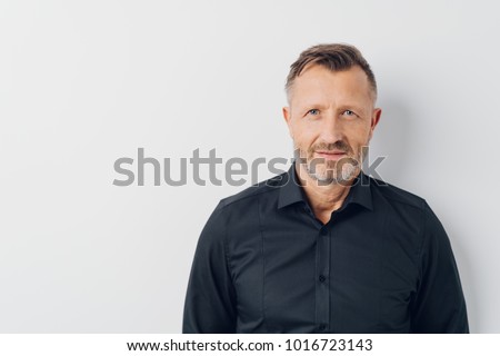 Head and shoulders portrait of a bearded middle-aged man looking thoughtfully at the camera over a white studio background with copy space