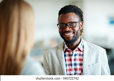 Head and shoulders portrait of cheerful bearded businessman in casualwear having conversation with his female colleague, blurred background - Shutterstock ID 590722742