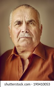 Head And Shoulders Portrait Of An Elderly Man With A Moustache Looking Directly At The Camera With A Serious Expression