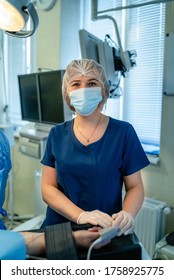 Head and shoulders portrait of female doctor wearing protective mask and looking at camera. Posing against medicalequipment background. Copy space