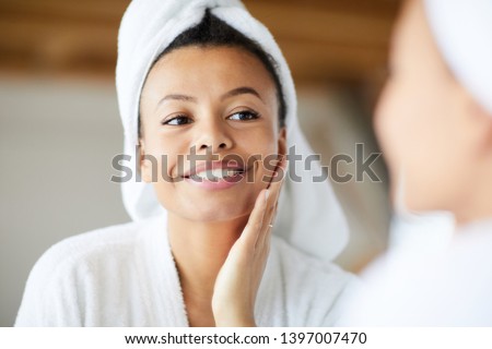 Head and shoulders portrait of  smiling Mixed-Race woman looking in mirror during morning routine, copy space
