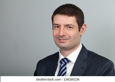 A Head And Shoulders Shot Of A 40 Year Old Business Man In A Suit And Shirt With Blue Tie.