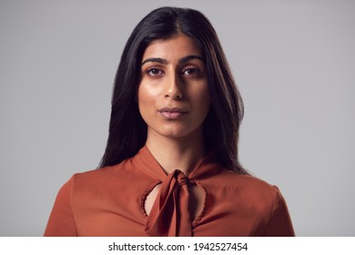 Head And Shoulders Studio Portrait Of Serious Young Businesswoman Against Plain Background