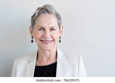 Head And Shoulders View Of Beautiful Older Woman With Short Grey Hair And Beige Jacket Against Neutral Background (selective Focus)