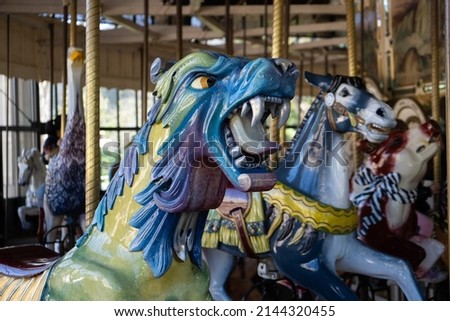 Head of a snarling Carousel creature - Gryphon, Wyvern or Dragon - in multiple colors, yellow, blue, green, purple, with silver teeth