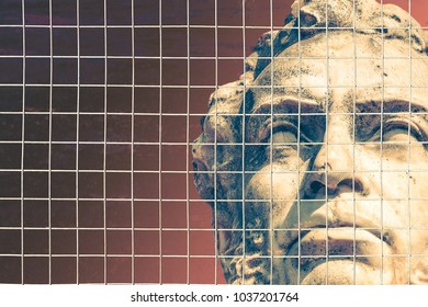 Head of a stone statue behind bars. The concept of freedom