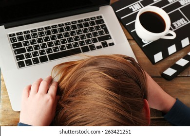 Head Of Tired Scriptwriter On Laptop At Wooden Desk Background