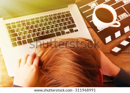 Head of tired scriptwriter on laptop at wooden desk background