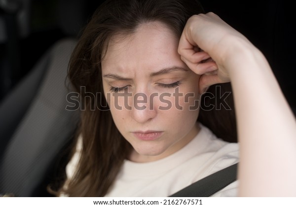 Headache in the car.\
The female driver is holding on to her head in pain. Stress behind\
the wheel of a vehicle