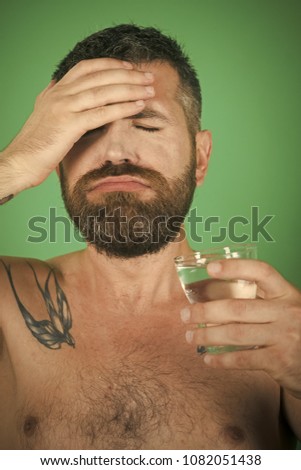 headache of man with beard on face drink water from glass on green background, healthcare and life source, hangover and thirst, refreshing
