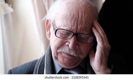 Headache in an old gray-haired grandfather, his age is 85 years.