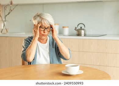 Headache pain. Unhappy middle aged senior woman suffering from headache sick rubbing temples at home. Mature old senior grandmother touching temples experiencing stress Woman feeling pain hurt in head - Powered by Shutterstock