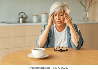 Headache pain. Unhappy middle aged senior woman suffering from headache sick rubbing temples at home. Mature old senior grandmother touching temples experiencing stress Woman feeling pain hurt in head - Powered by Shutterstock