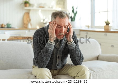 Headache pain. Unhappy middle aged senior man suffering from headache sick rubbing temples at home. Mature old senior grandfather touching temples experiencing stress. Man feeling pain hurt in head