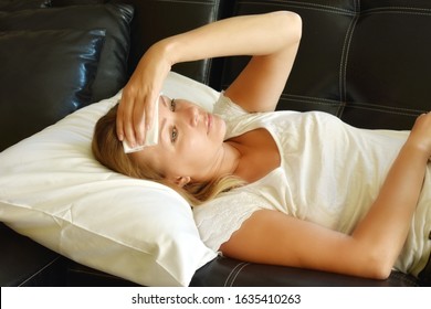 Headache. Woman Lying On Sofa With Tissue On His Forehead. Suffering From Headaches. Chronic Migraine. Early Menopause. A Tired Woman. Coronavirus