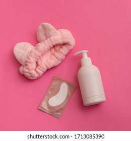 
Headband, cream jar and eye patches on pink background. 
Face care concept