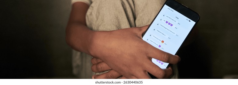 Header of hand holding smartphone while browsing messages on social media. Visible screen displaying emojis and text messages