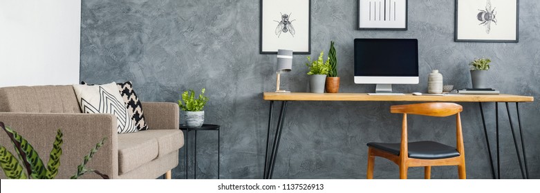 Header Of A Monochromatic Living Room Interior With A Cozy Sofa And A Stylish Home Office Area With A Wooden Desk And Posters On A Gray Wall