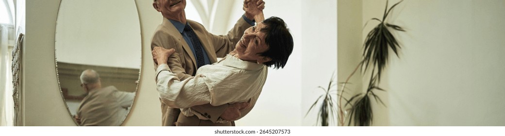 Header of smiling elderly couple dancing and enjoying their time together, as seen through a large mirror reflecting their joyful expressions and movements captured indoors