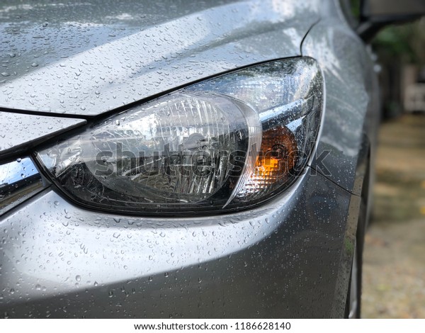 Headlamps of car has water drops,\
on rainy day make the view or scenery worse. Selective\
focus.