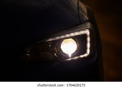 The Headlight Of The Car, Turned On The Light On The Background Of A Dark Night