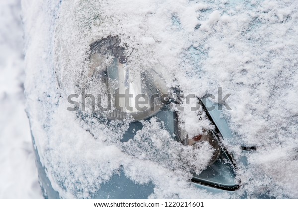 Headlight of a frozen car covered with snow\
close-up outdoors