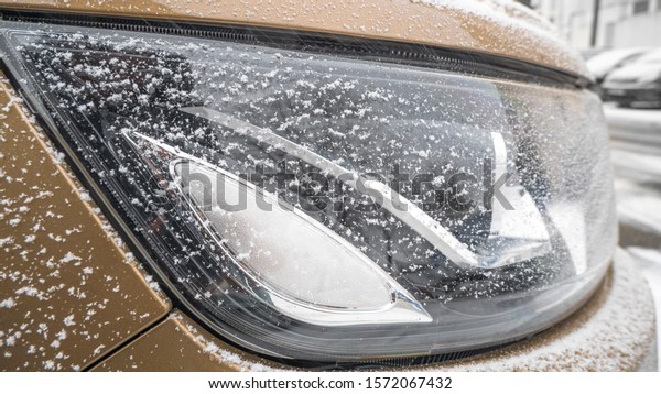 headlight of the gold color car in winter\
covered with snow\
closeup.