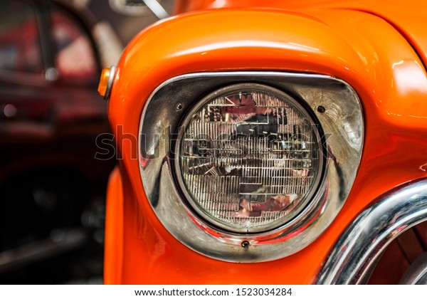 Headlight lamp vintage\
car. Classic car headlight. Close-up of headlights of orange\
vintage car.\
Exhibition.