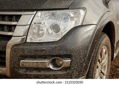 Headlight Of A Modern Gray Car Covered In Mud.