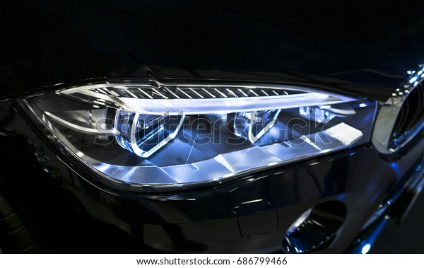 Headlight of a\
modern sport car. Front view of luxury sport car. Car exterior\
details. The front lights of the\
car
