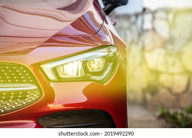 Headlight And Radiator Grille Of A Beautiful Red Car With Yellow Tint