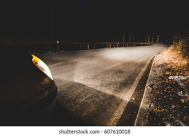 the headlights of a car on mountain road in the night - concept driving safety