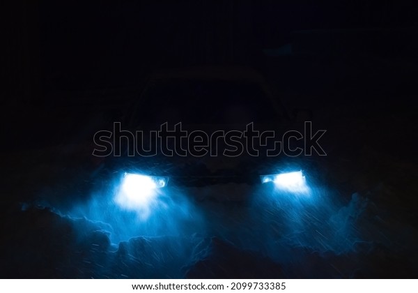 the headlights of the car shine through the snow\
into the blizzard