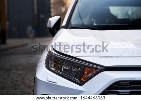 Headlights and hood of sport white car with silver stars
