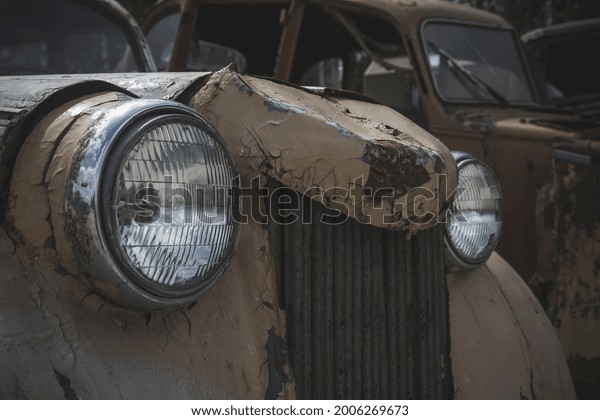 Headlights and old front of\
an abandoned car. Old rusty car. A beautiful element of an\
abandoned car.